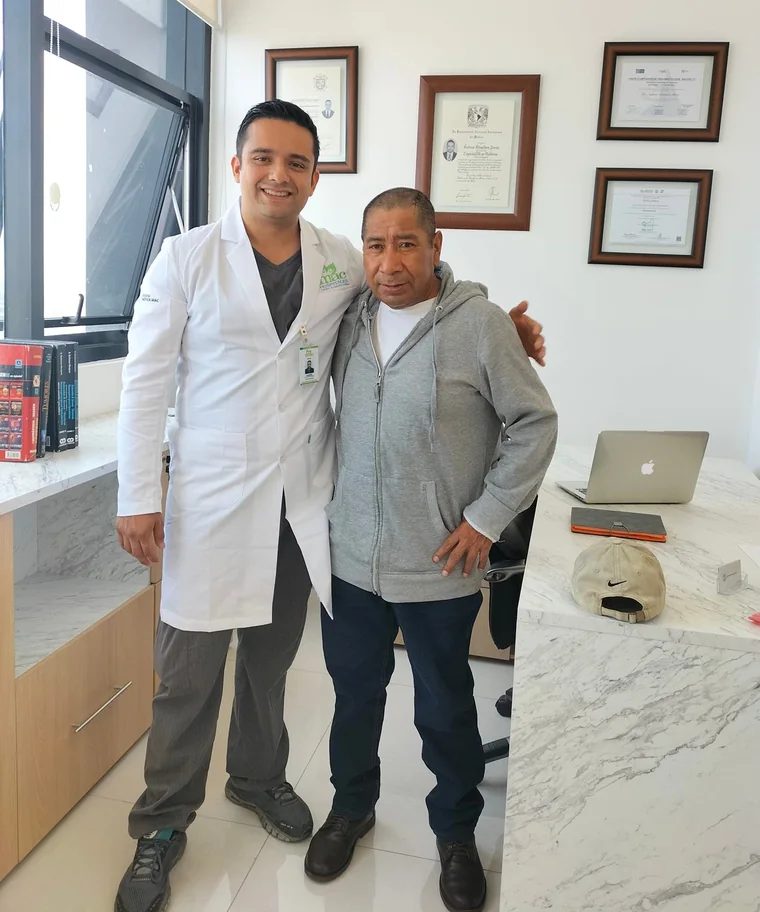 Dr. Andrés Alcántara Pérez con un paciente en su consultorio, con sus diplomas de especialidad
